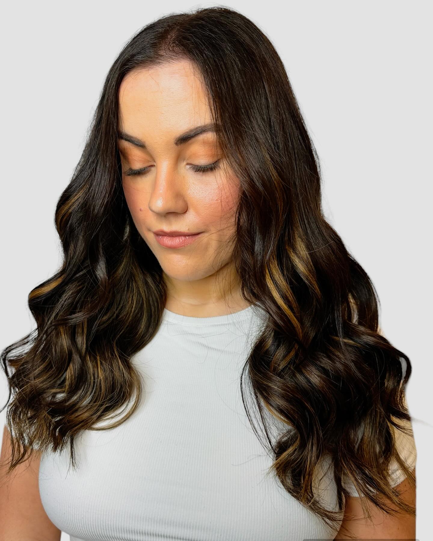 Glossy brunette balayage with soft caramel ribbons and polished waves