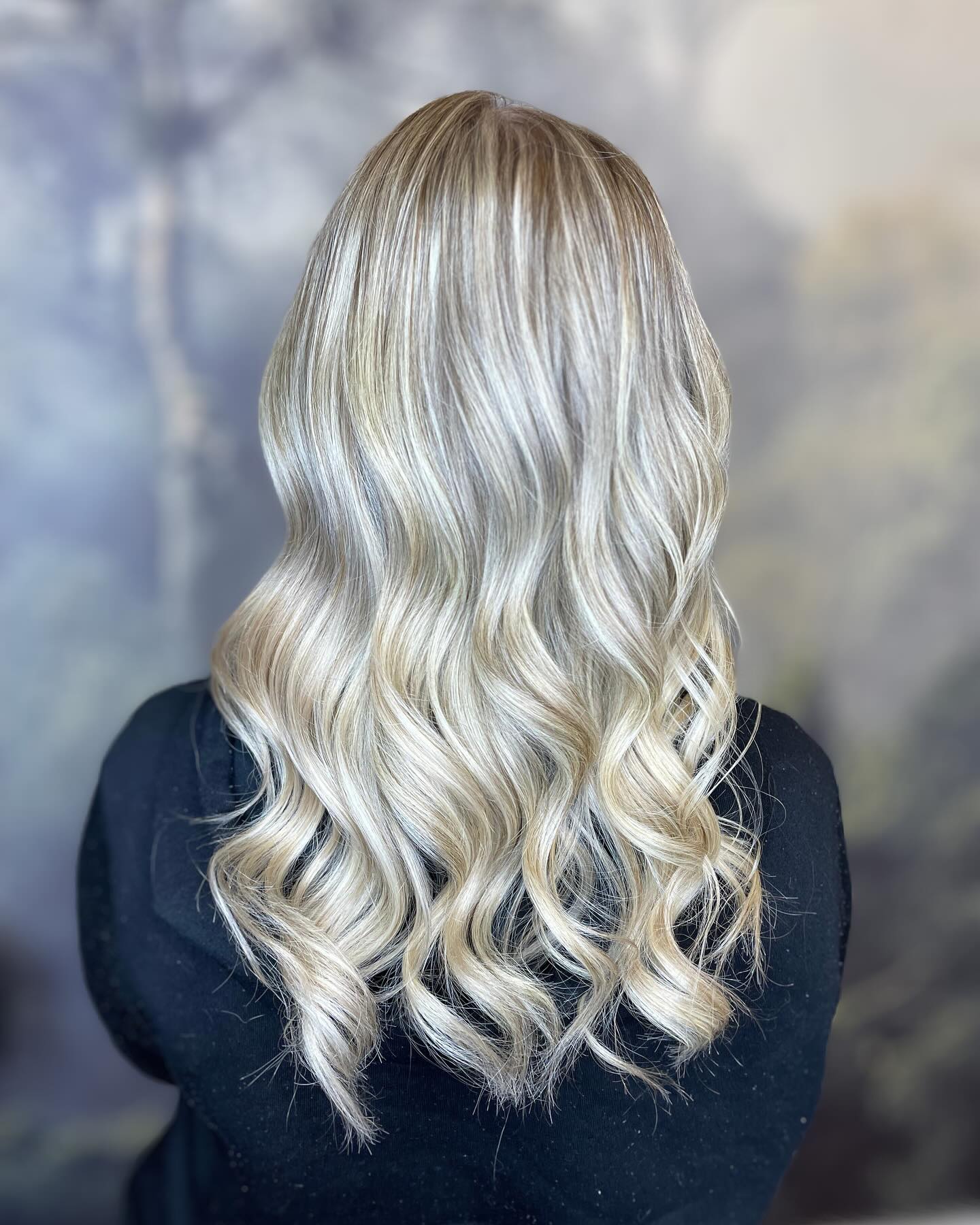 Bright icy blonde balayage with dimensional root melt and soft curls