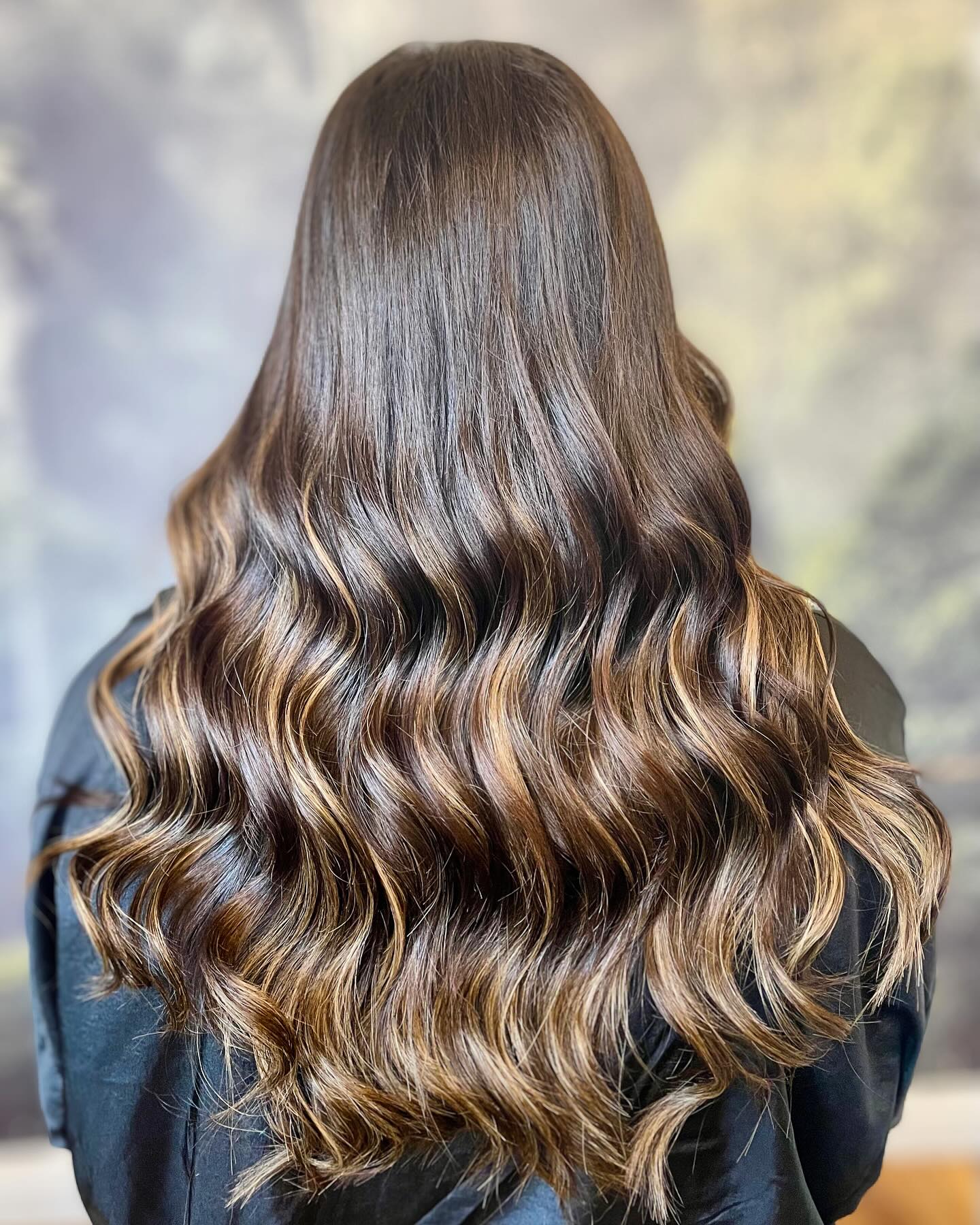 Dark brunette balayage with caramel ribbons and beach waves
