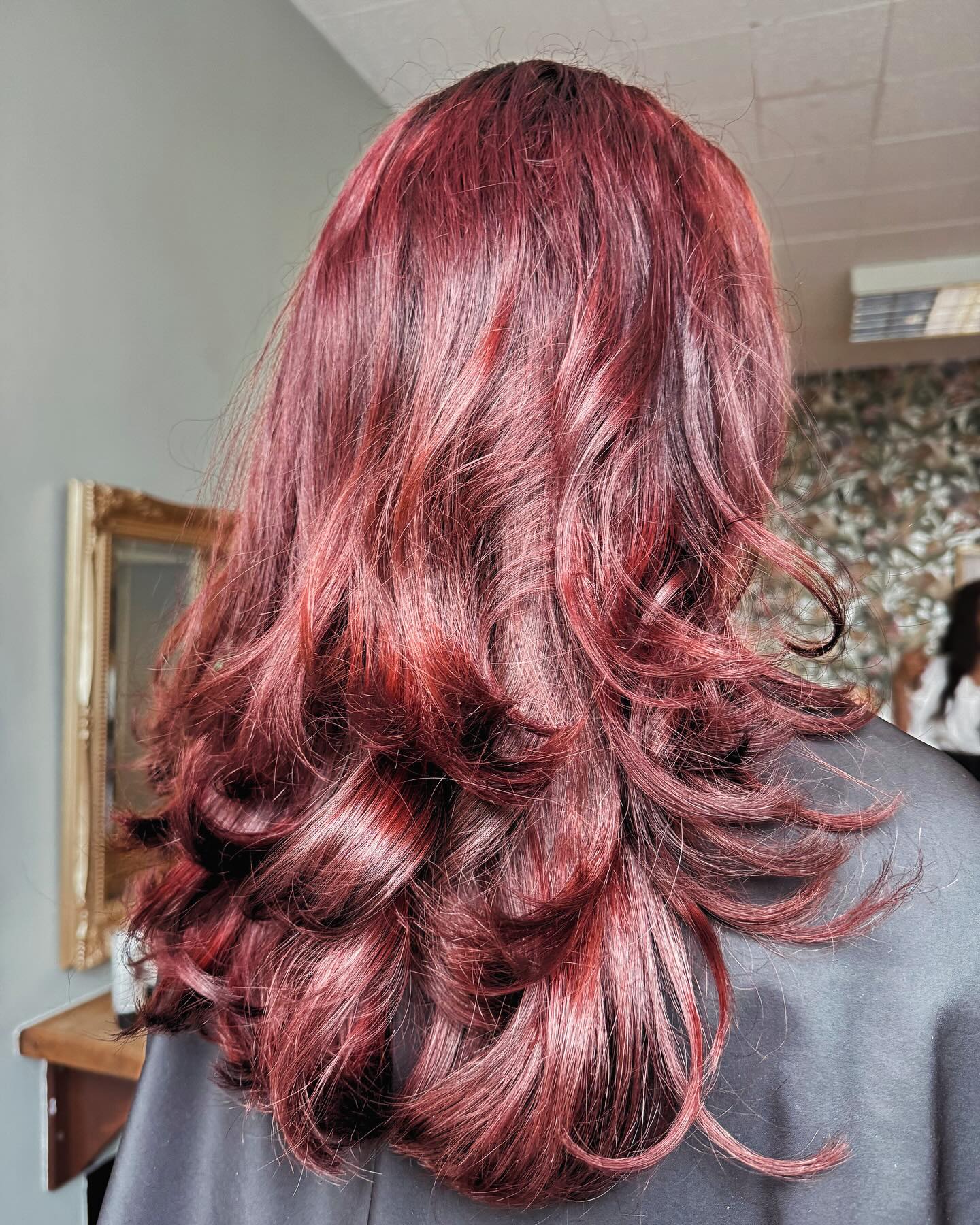 Deep burgundy red hair colour with layered styling and glossy finish