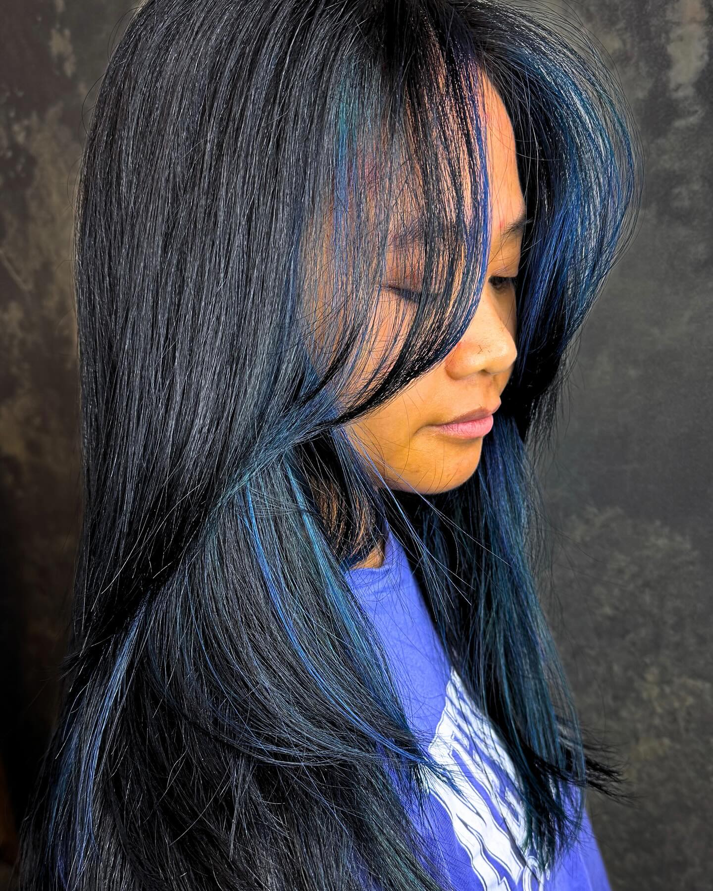 Black hair with blue face-framing panels and layered styling