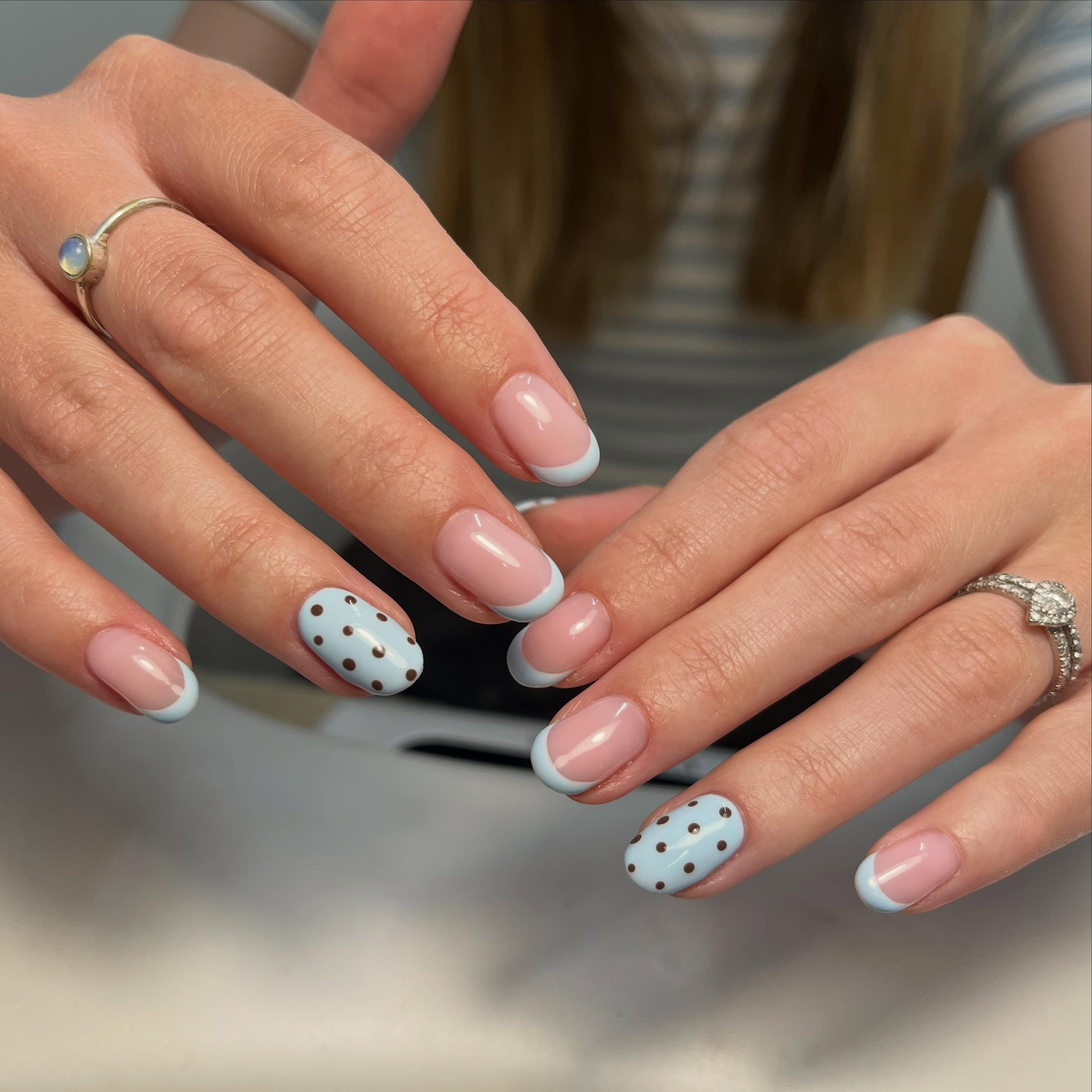 Soft pink French manicure with pastel blue tips and polka dot accent nails, a clean and elegant modern look