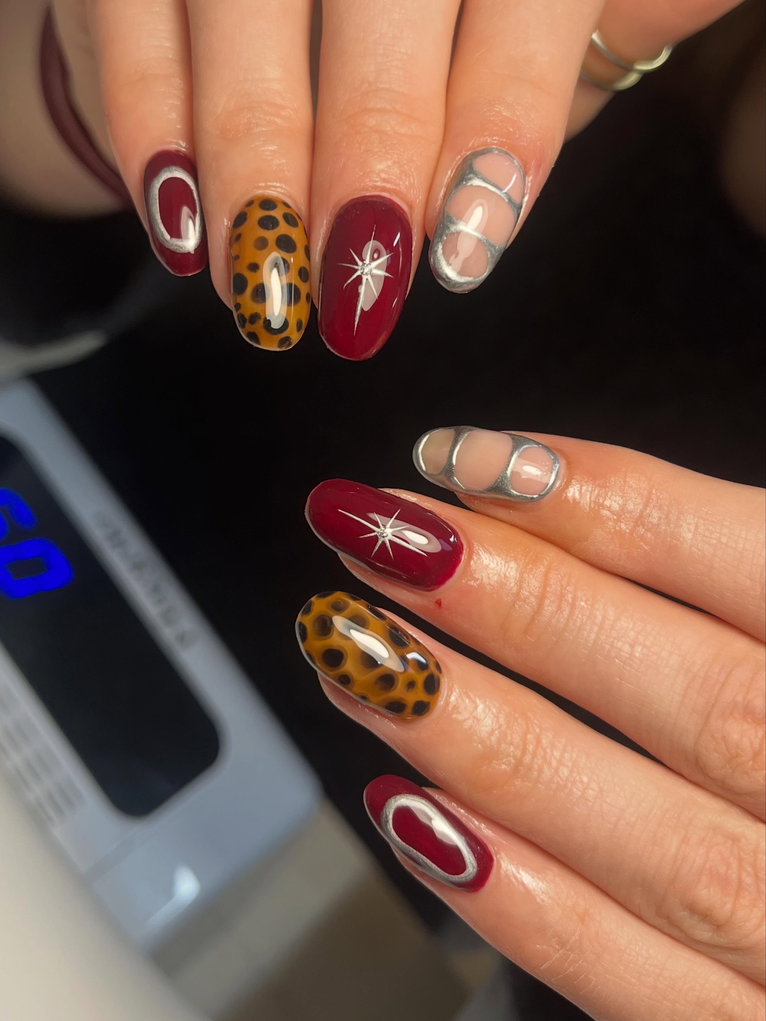 Burgundy, silver chrome and leopard print nail art with celestial starburst details on glossy almond-shaped nails