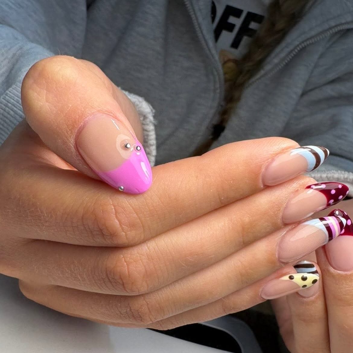 Abstract French tip nails in pink, burgundy, cream and chocolate brown with rhinestones and playful geometric patterns