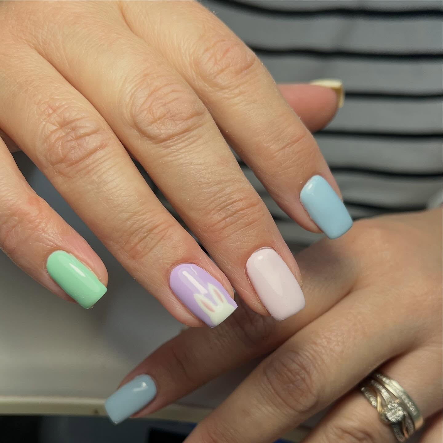 Pastel spring nails with mint green, baby blue, lilac and soft pink gel polish on square-shaped nails