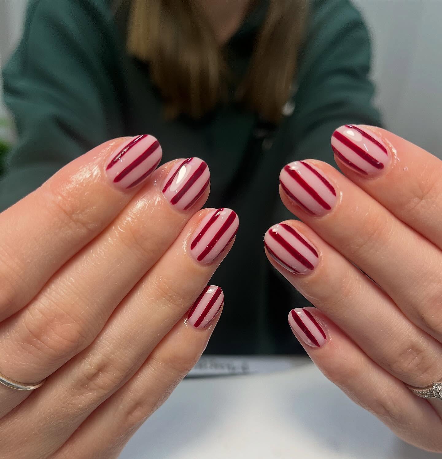 Minimalist burgundy striped nail art over a sheer pink base, a chic and modern manicure